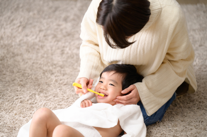 母親に仕上げ磨きをしてもらう男の子